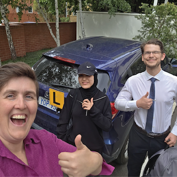 Three people giving thumbs up beside an L-plate car after a driving lesson.